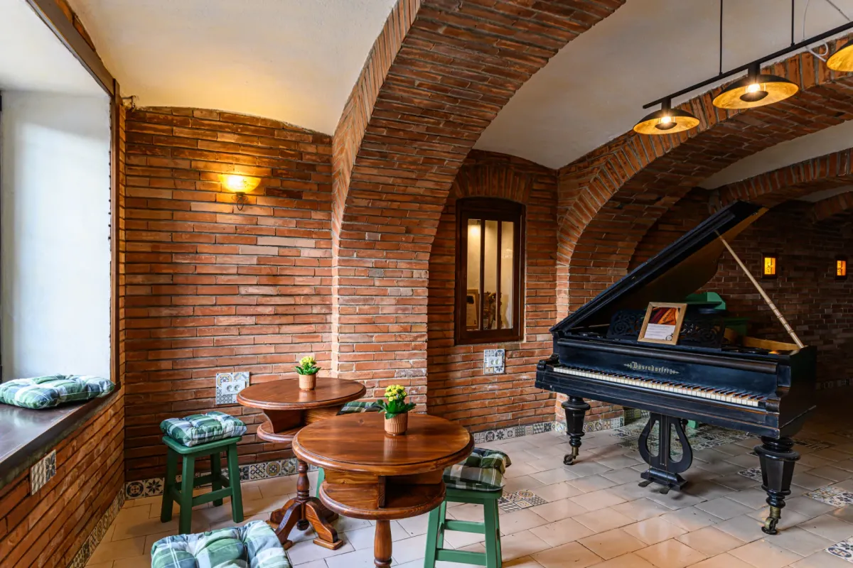 Sala de mese a Hanului Bucuriei, cu arcade de cărămidă, mese din lemn și pian.